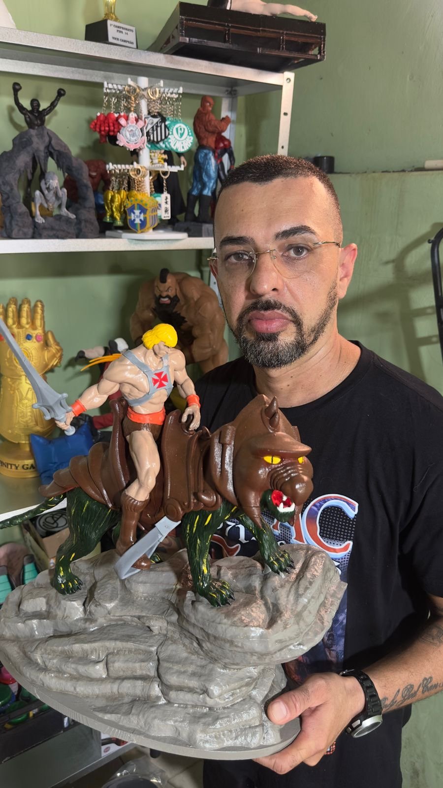 Eduardo da Silva de Oliveira, o Dú, fundador do Dart Studio 3D, segurando um diorama de He-Man montado no Gato Guerreiro