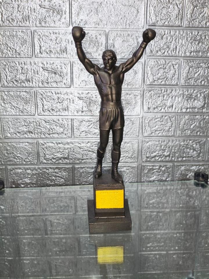 Estátua comemorativa de Rocky Balboa com os braços erguidos sobre pedestal com placa