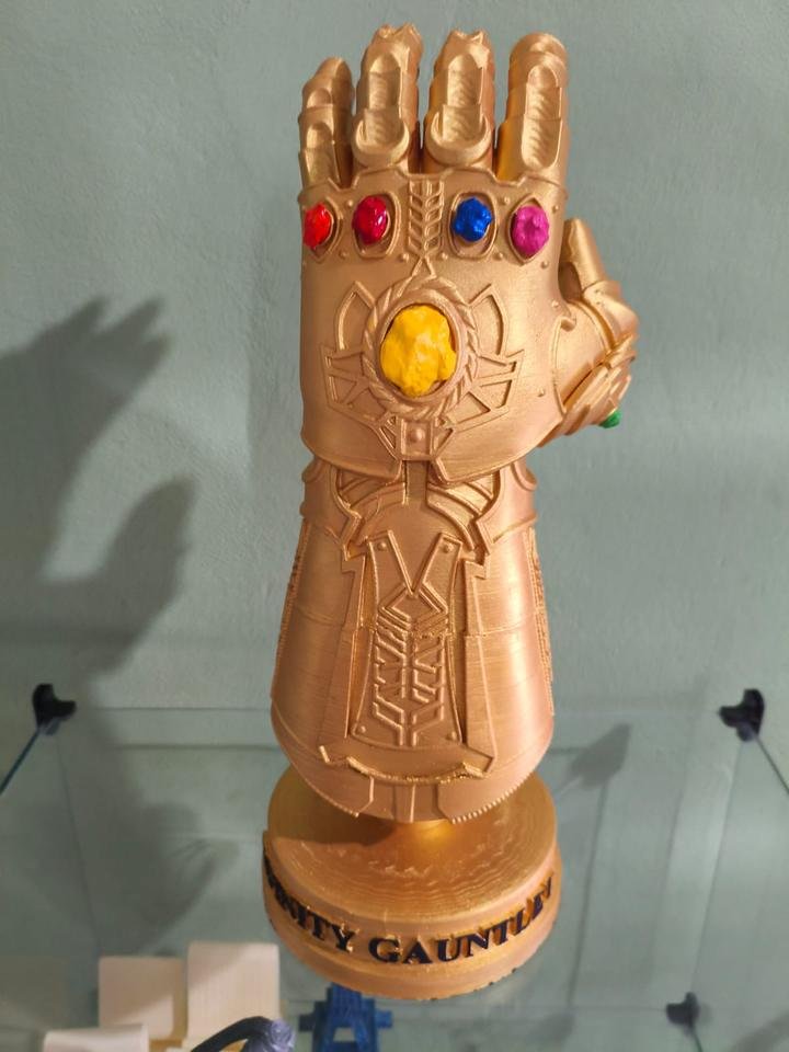 Manopla do Infinito dourada com gemas coloridas, peça de exibição em pedestal